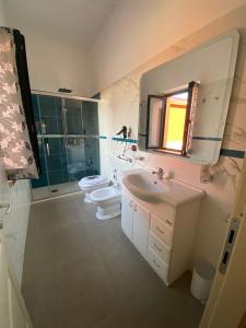 bagno con 2 servizi igienici, lavandino e specchio di Hostaria delle Memorie a Curinga