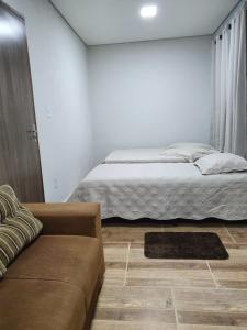 a bedroom with a bed and a couch at Suítes Nativa STL in São Thomé das Letras