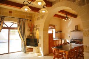 cocina con pared de piedra y mesa con sillas en Centre Island Holiday Home with private pool and hot tub, en Kerċem