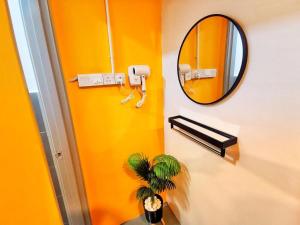 Baño amarillo con espejo y planta en The Cocoon Capsule Hotel, en Cameron Highlands