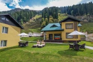 a yellow house with chairs and tables on a lawn at Arco Hotels & Resorts sonamarg in Sonāmarg