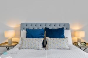 a bedroom with a bed with blue pillows and two lamps at 1 Bed- Hawkyns By Pureserviced in Plymouth