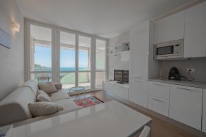 un soggiorno bianco con divano e cucina di Appartamento incantevole con piscina a Vallecrosia