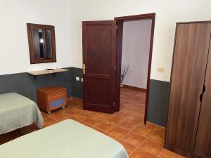 a room with two beds and a door and a mirror at Casa de campo Yuco in Tinajo
