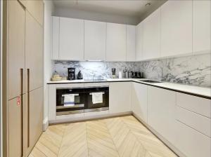 a kitchen with white cabinets and a wooden floor at Luxurious Covent Garden Penthouse in London