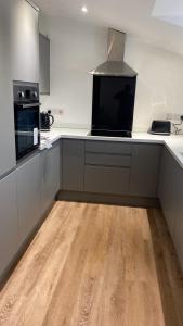 a kitchen with white counters and a wooden floor at Town Centre Apartment in Leek
