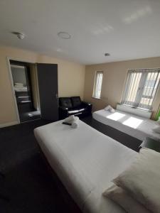 ニューカッスル・アンダー・ライムにあるLymedale Suites Studios & Aparthotel in NEWCASTLE UNDER LYME & STOKEのベッド2台とソファが備わるホテルルームです。