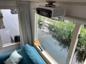 a room with a window with a tv and a couch at Woonark Westeinder with kayaks close to Schiphol Airport in Aalsmeer