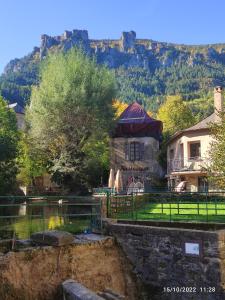 a house with a pond in front of a mountain at Grand appartement de charme avec parking privé in Florac
