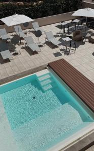 a swimming pool with chairs and tables and umbrellas at Elitis House - Suite & Spa in Nova Milanese