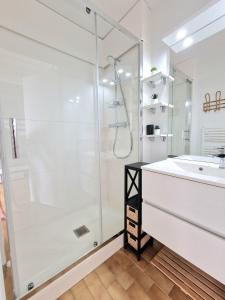 biała łazienka z prysznicem i umywalką w obiekcie Appartement 1ere ligne piscine terrasse au bord de la plage front de mer avec 6 vélos w mieście Palavas-les-Flots