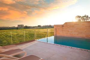 a pool with chairs on a patio with a view at Inni Holiday Home with Infinity Pool in Għarb