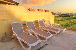 une rangée de chaises alignées sur un mur dans l'établissement Inni Holiday Home with Infinity Pool, à L-Għarb