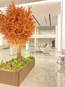 uma árvore no meio de um lobby com mesas e cadeiras em فندق هوليداي الخليج النجاح em Riade