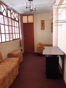 a room with a couch and a table and windows at Hostal Vista al Lago Titicaca Puno in Puno