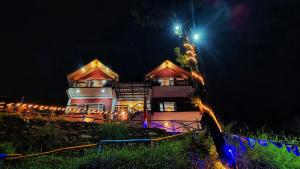 a house is lit up at night with lights at Gadegal Homestay Narkanda - Rooms & Pahadi Café in Shimla