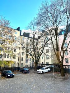 un grupo de autos estacionados en un estacionamiento frente a un edificio en Villa Centralen, en Helsinki