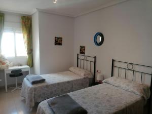 1 Schlafzimmer mit 2 Betten, einem Schreibtisch und einem Fenster in der Unterkunft Sea and Relax Apartment By MM in Torrevieja