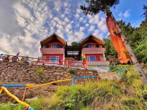 um edifício cor-de-rosa no topo de uma parede de pedra em Gadegal Homestay Narkanda - Rooms & Pahadi Café em Shimla