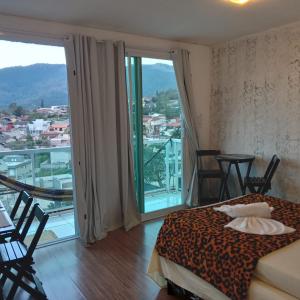 a bedroom with a bed and a balcony with a view at Hospedagem Sol Nascente in Atibaia
