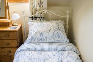 een slaapkamer met een bed met een blauwe en witte sprei bij Batney Farm Cottage, Meshaw, South Molton in South Molton