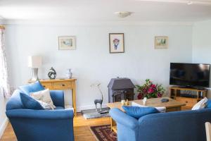 a living room with two blue chairs and a table at Batney Farm Cottage, Meshaw, South Molton in South Molton