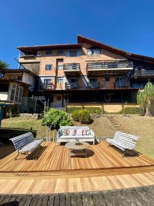 una terraza de madera con 2 bancos y una mesa en Pousada Vale das Flores en Nova Friburgo