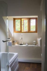 baño blanco con lavabo y ventana en Batney Farm Cottage, Meshaw, South Molton, en South Molton