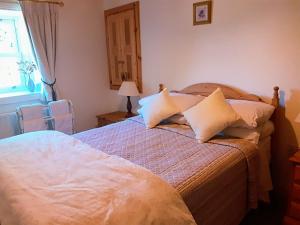 een slaapkamer met een bed met kussens en een raam bij Lackaroe Cottage in Garrykennedy