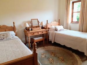 um quarto com 2 camas e uma secretária com um espelho. em Fraoch Cottage em Garrykennedy
