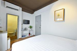 a bedroom with a white bed and a bathroom at The Noble Swan Wood Park Hotel in Ho Chi Minh City