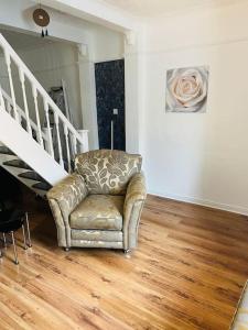 a living room with a chair and a staircase at The White House - Cheerful 3 Bedroom home in Wigan - Ince - sleeps 7 - parking - Work space - Great motorway links in Ince-in-Makerfield