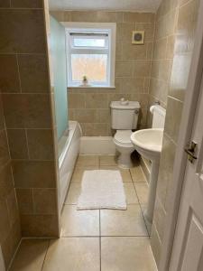 a bathroom with a toilet and a tub and a sink at The White House - Cheerful 3 Bedroom home in Wigan - Ince - sleeps 7 - parking - Work space - Great motorway links in Ince-in-Makerfield