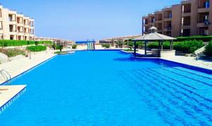 a large blue swimming pool with a gazebo at Cozy Chalet in El Ain El Sokhna شالية بالعين السخنة in Ain Sokhna