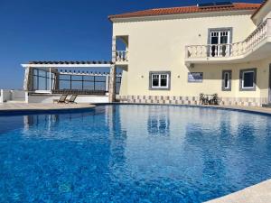 a large swimming pool in front of a house at Casa das Rosas in Carvoeira