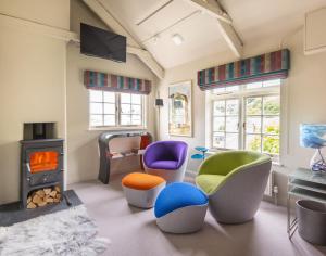 a living room with colorful chairs and a stove at Crow's Nest in Port Isaac
