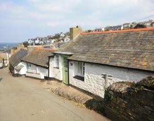 a row of white houses with green doors on a street at Crow's Nest in Port Isaac