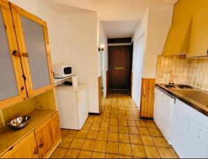 cocina con armarios blancos y suelo de baldosa en Grand Studio aux pieds des pistes sans vis à vis, en Les Gets