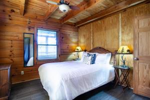 une chambre avec un lit blanc et des murs en bois dans l'établissement Pet-friendly Rustic Cabin with Game Room and Deck, à Pigeon Forge