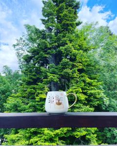 a coffee cup sitting on a rail in front of a tree at Pine Tree Residence in Sinaia