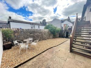 d'une terrasse avec des chaises, une table et un mur. dans l'établissement Arthurs Cottage -Charming Courtyard Cottage in the heart of Kendal, The Lake District, à Kendal