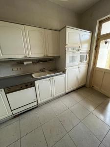 a kitchen with white cabinets and a sink and a window at Bel appartement avec vue sur parc - Tour Japonaise in Brussels