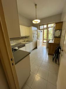 a kitchen with white cabinets and a tile floor at Bel appartement avec vue sur parc - Tour Japonaise in Brussels