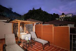 a patio with two chairs and a bath tub at Luna Volcán, Adventure SPA in Baños