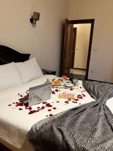 Una cama con rosas con un portátil. en Hyde Park House Hotel, en Alejandría