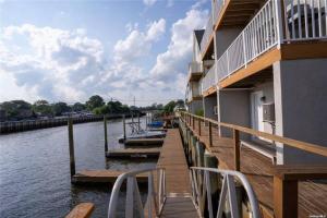 a dock with boats on the water next to a building at Yachtsman Cove Water Front 3 Bedrooms House Features 3 Levels Living Space in Freeport NY in Freeport