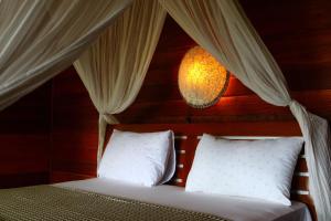 a bed with white pillows and a chandelier at Biru Meno Beach Bungalows in Gili Meno