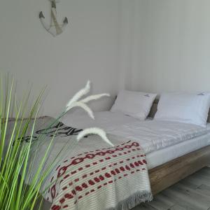 a bedroom with a bed with white sheets and a plant at Łebskie Zacisze - apartamenty Łebska Ostoja- Piaskowa in Żarnowska