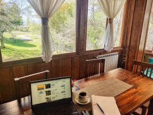 a laptop computer sitting on a wooden table with a window at Posada del Ñireco in San Carlos de Bariloche