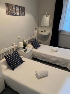 two beds in a room with a sink at Hostal Parisien Las Ramblas in Barcelona